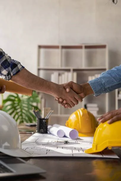 Construction professionals agreeing on a building project beside plans and safety helmets